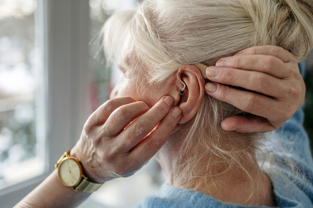 Senior woman applying hearing aid