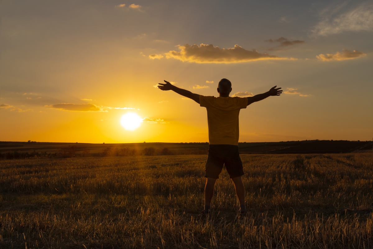 Man with hands outstretched embracing sunset
