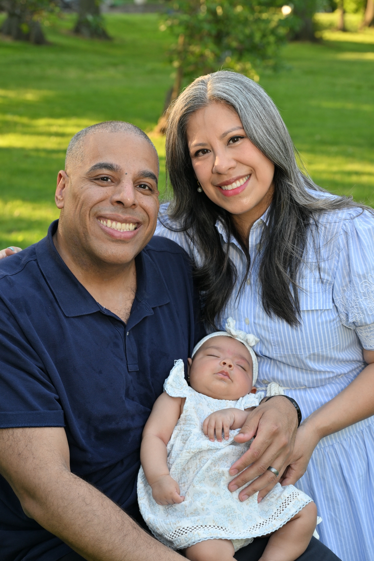 A portrait of a couple with their newborn baby in an outdoor setting